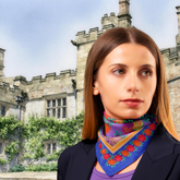 Woman wearing a colourful scarf in front of a castle-like building, Haddon Hall, Peak district.